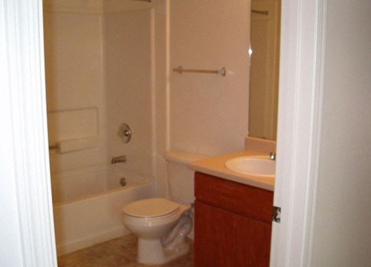 A white toilet sits in a bathroom next to a sink at Roosevelt Commons Apartments, Arizona