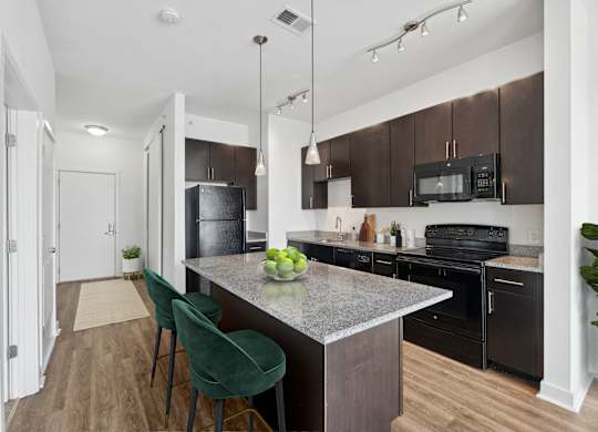 a kitchen with black appliances and a marble counter top with green chairs at Fort Totten Square, Washington DC, 20011