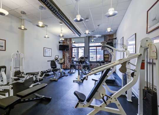 A gym with a variety of equipment including treadmills, weights, and exercise machines.