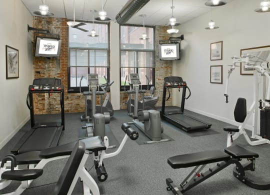 a gym with weights and exercise equipment in a room with windows at Tindeco Wharf, Baltimore, MD