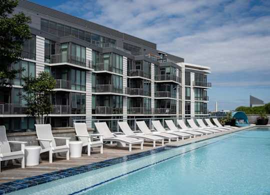 A row of white lounge chairs are set up on a pool deck. at Dock 79, Washington, DC
