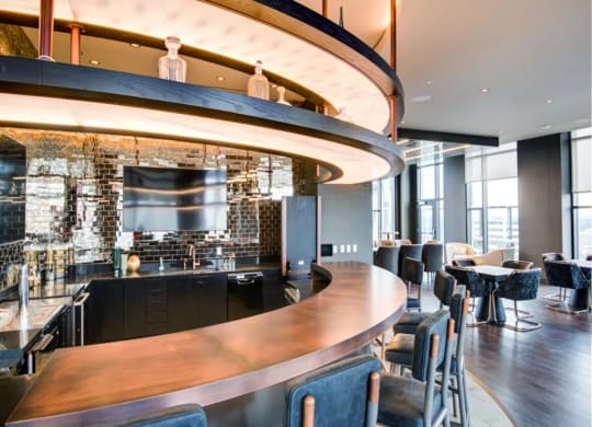 a curved bar in a restaurant with blue chairs and a tv on the wall at The Boro, Virginia