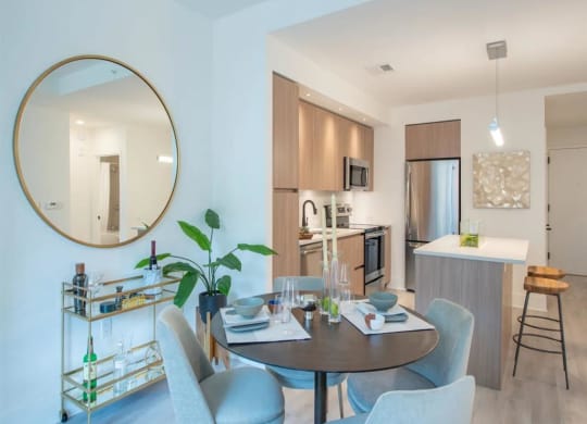 a dining room with a table and chairs and a kitchen in the background at The Boro, Tysons, VA