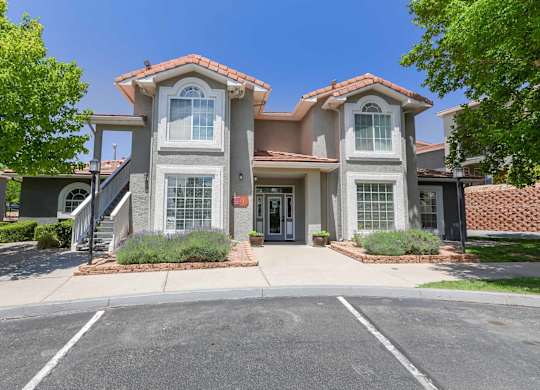 A two-story house with a red tile roof and a driveway in front at West Park Apartments, Albuquerque