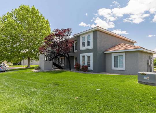 A grey house with a red roof and a green lawn at West Park Apartments, Albuquerque