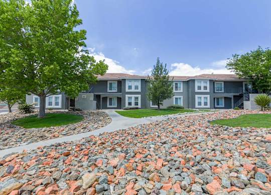 A large grey building with a stone pathway in front at West Park Apartments, Albuquerque