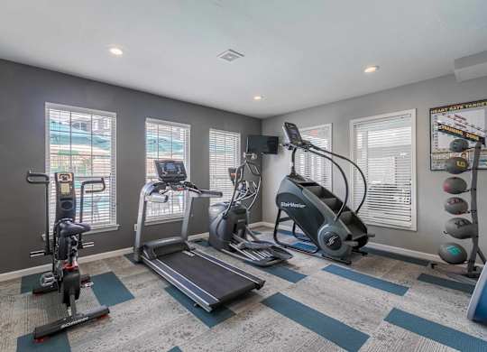 A spartan room with a treadmill, exercise bike, and other equipment at West Park Apartments, Albuquerque