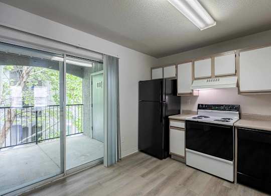 A kitchen with black appliances and white cabinets at West Park Apartments, Albuquerque