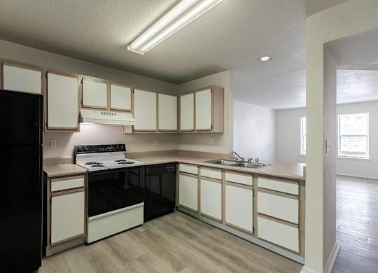 A kitchen with black appliances and white cabinets at West Park Apartments, Albuquerque