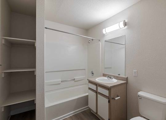 A small bathroom with a toilet, sink, and medicine cabinet at West Park Apartments, Albuquerque