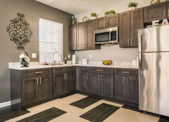 A kitchen with brown cabinets and a white fridge at West Park Apartments, Albuquerque, NM, 87114