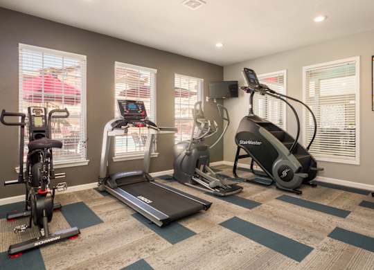 A home gym with a treadmill, elliptical trainer, and stationary bike at West Park Apartments, Albuquerque, New Mexico