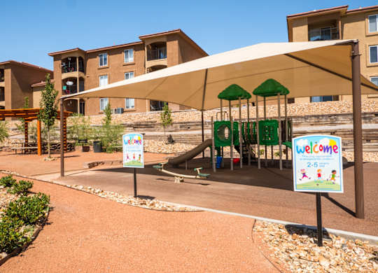 A playground area with a slide and a sign at West Park Apartments, Albuquerque