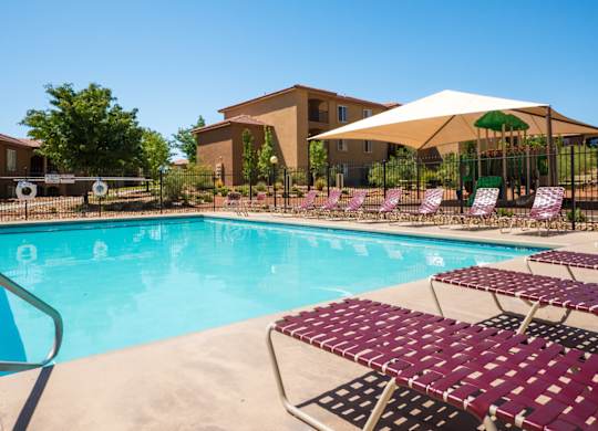 A pool with a white umbrella and red chairs at West Park Apartments, Albuquerque, NM, 87114