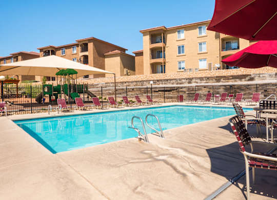 A pool with a red umbrella and a slide at West Park Apartments, New Mexico 87114