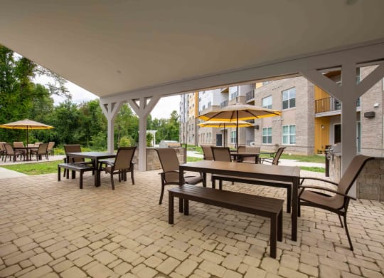 a covered patio with tables and chairs and umbrellas at Woodmore Grand, Bowie