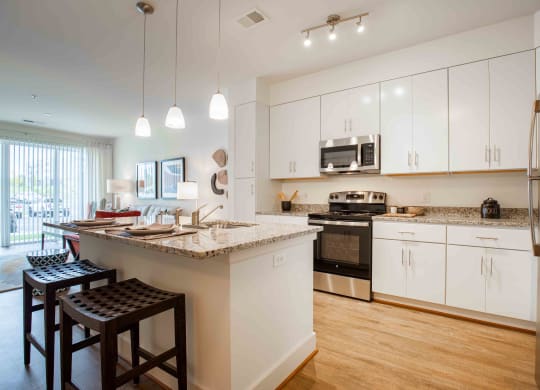 a kitchen with white cabinets and a large island with granite countertops  at Woodmore Grand, Bowie, 20721