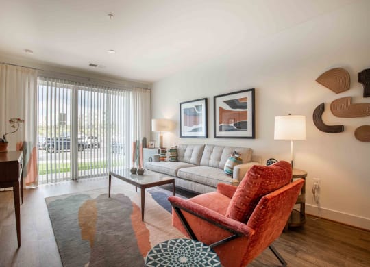a living room with a couch and a chair and a window at Woodmore Grand, Bowie