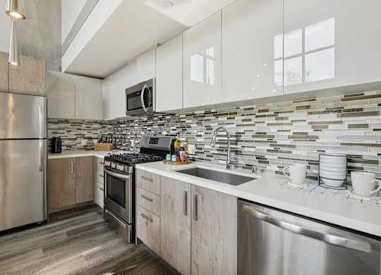 A modern kitchen with a stainless steel refrigerator and a tiled backsplash. at The Mansfield at Miracle Mile, Los Angeles