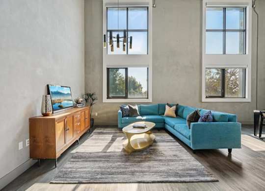 A living room with a blue couch and a wooden cabinet. at The Mansfield at Miracle Mile, California