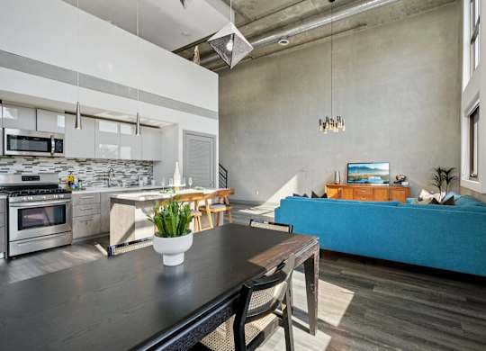 A modern kitchen with a dining table and a bed in the background. at The Mansfield at Miracle Mile, Los Angeles