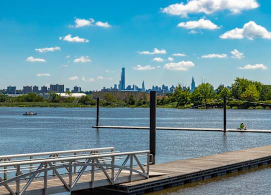 A dock extends into a calm body of water with a city skyline in the distance at Vermella Lyndhurst apartments, New Jersey, 07071
