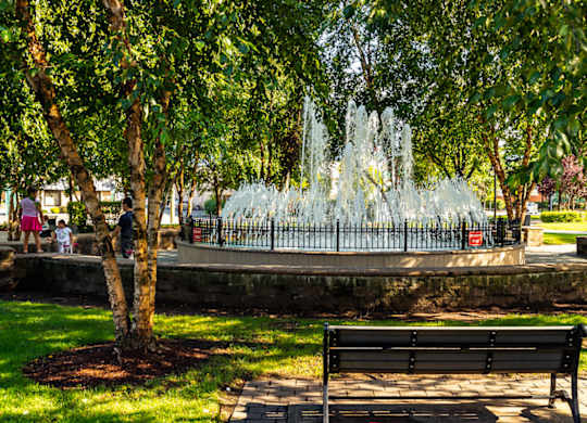 A fountain in a park with a bench in the foreground. at Vermella Lyndhurst apartments, New Jersey