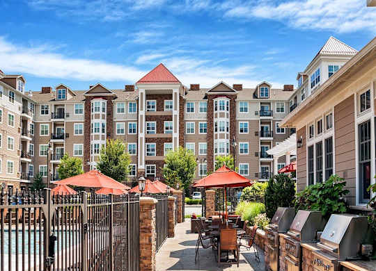 A large building with a pool in front of it at Vermella Lyndhurst apartments, New Jersey