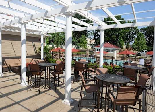 A patio with tables and chairs under a white pergola at Vermella Lyndhurst apartments, Lyndhurst 07071