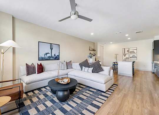 A living room with a white couch and a blue and white rug.