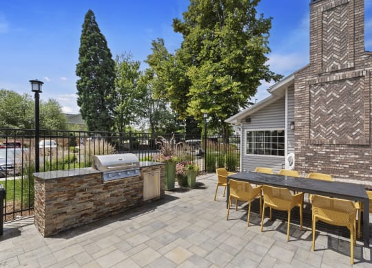 a patio with a grill and a table with yellow chairs