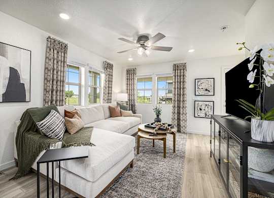 a living room with a white couch and a ceiling fan