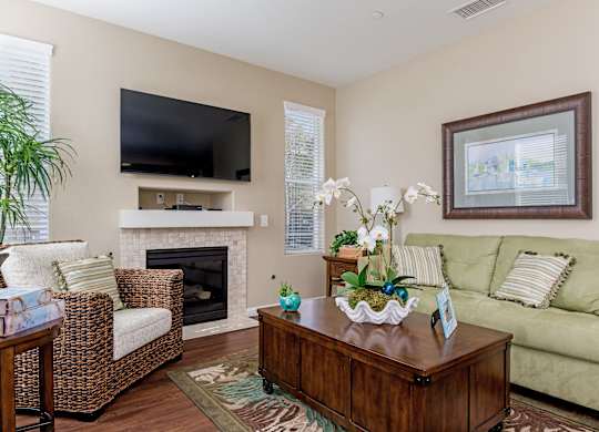A living room with a fireplace, a couch, a chair, a coffee table, and a television.