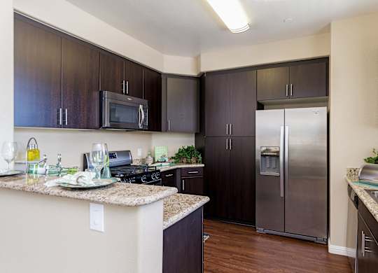 A kitchen with dark brown cabinets and a granite counter top.