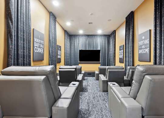 A home theater with grey seats and a black screen.