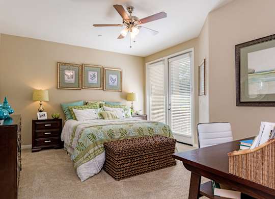 A bedroom with a bed, a chair, and a ceiling fan.