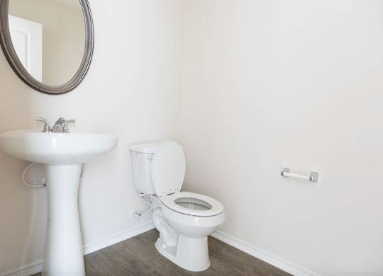 A white toilet sits next to a white pedestal sink in a bathroom.