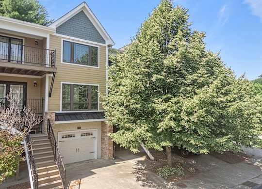 A house with a garage and a tree in front.