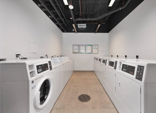 a laundry room with washers and dryers and a row of washing machines