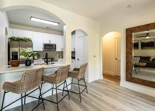 A kitchen with a counter and chairs.