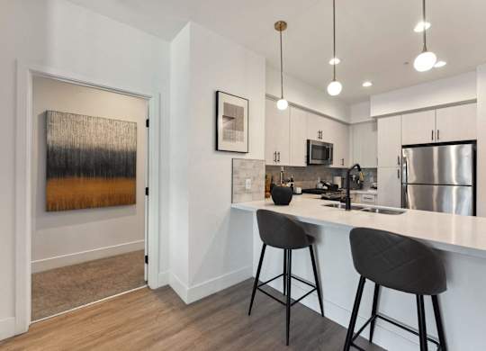 A kitchen with a white counter and bar stools.