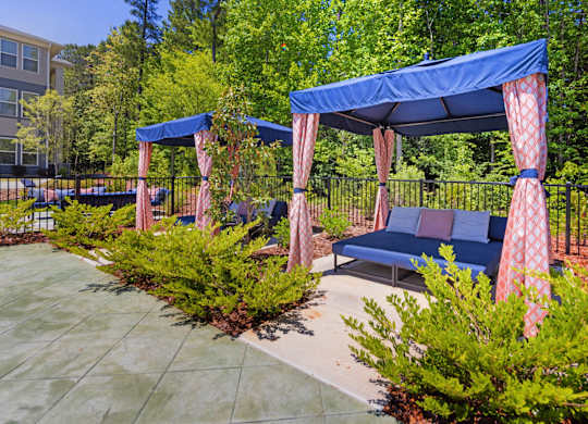 A blue canopy with red curtains is over a bench.