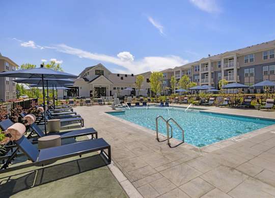 A large swimming pool surrounded by lounge chairs and umbrellas.