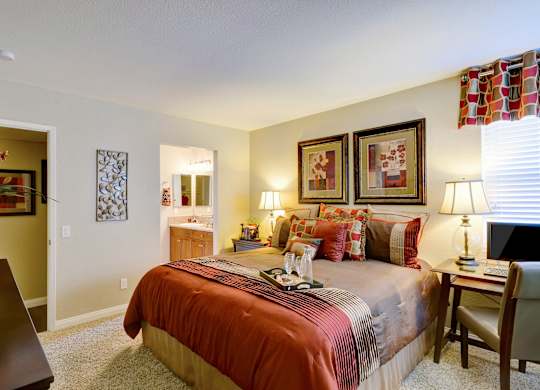 A bedroom with a bed, nightstands, and pictures on the wall.