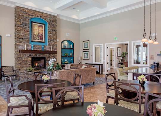 A room with a stone fireplace and a dining table set for six.