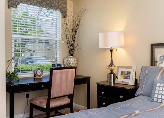 A bedroom with a bed, desk, chair, and window.