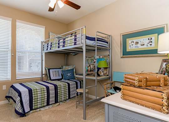 A room with a bed, a desk, and a fan.