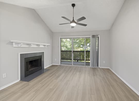an empty living room with a fireplace and a ceiling fan