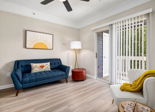a living room with a blue couch and a door to a balcony at Mariners Crossing, Raleigh, NC