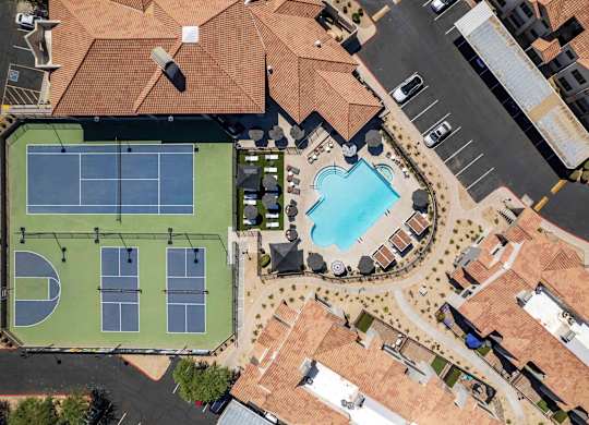 A tennis court with a pool and a building in the background.